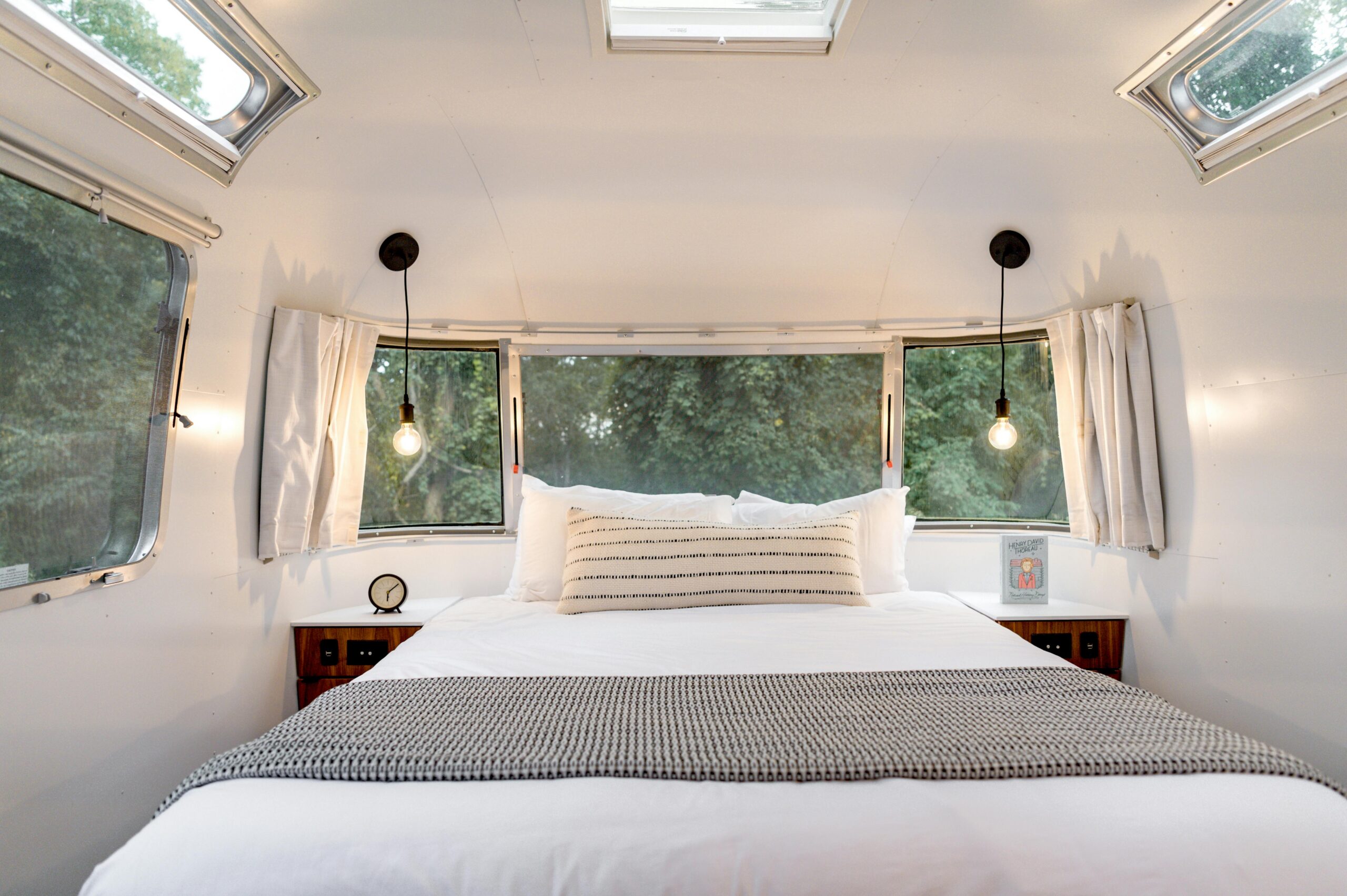 Trailbound mobile rv service comfortable bed setup with good lighting and electrical system in a stylish airstream trailer offering a cozy experience